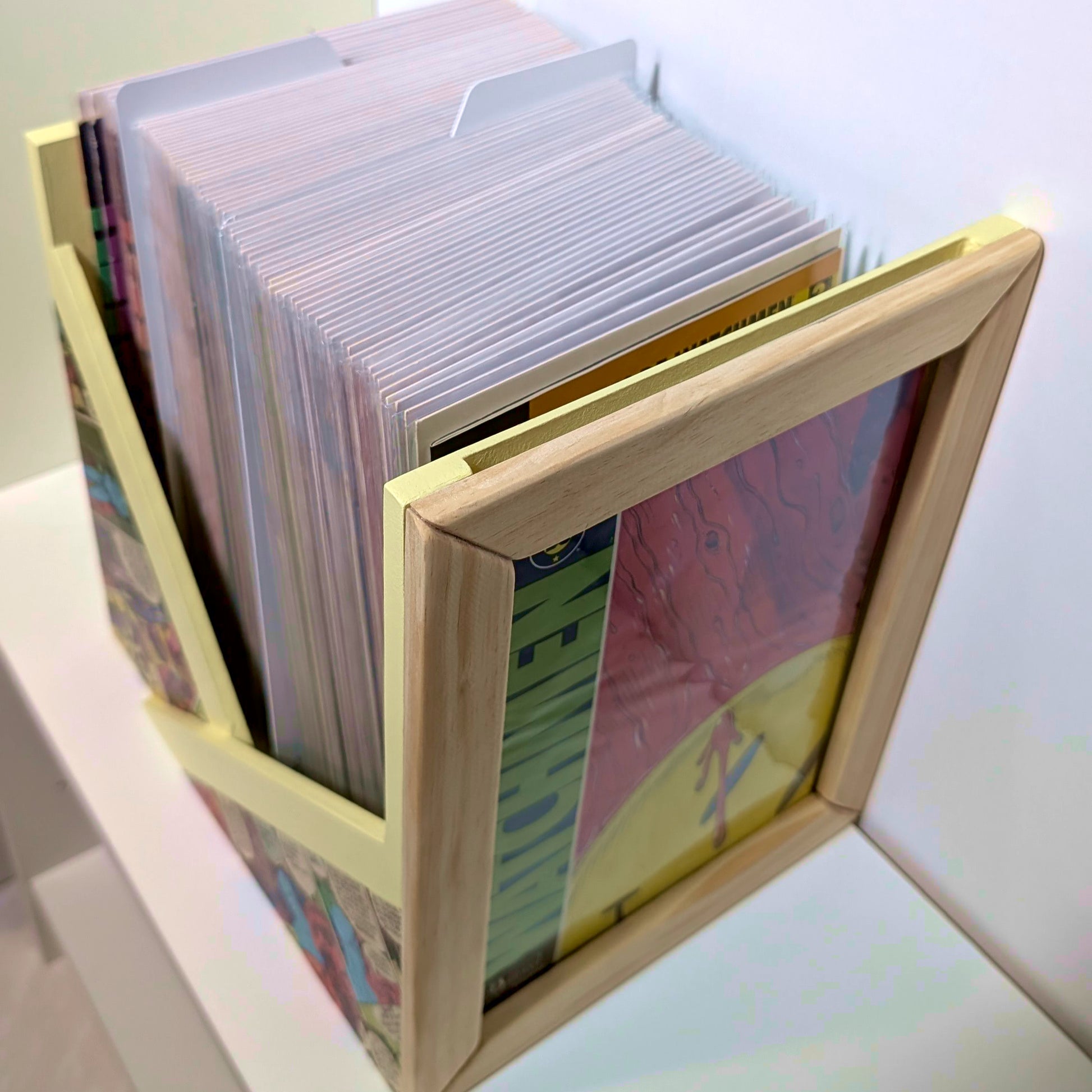 Vista superior de caja abierta para grapas llena de cómics enfundados, con marco frontal expositor.