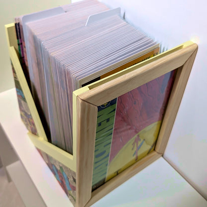 Vista superior de caja abierta para grapas llena de cómics enfundados, con marco frontal expositor.